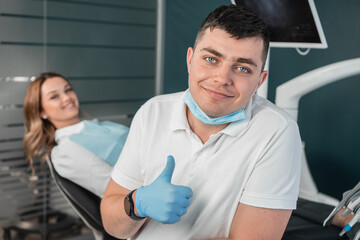 The dental clinic provides medical care and treatment of the highest level. The patient receives advice and high-quality treatment in a dental clinic. Dentist with patient looking at camera
