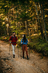 A multiethnic couple sets off on an invigorating hike, equipped with backpacks and walking poles to...