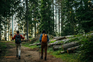A multiethnic couple sets off on an invigorating hike, equipped with backpacks and walking poles to conquer the challenging yet rewarding trail