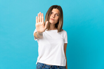 Young slovak woman isolated on blue background making stop gesture