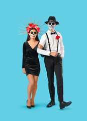 Young couple dressed for Mexico's Day of the Dead (El Dia de Muertos) on blue background