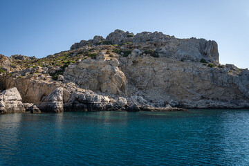 Fototapeta na wymiar Majestic Rock Formations of Rhodes: A sea-level view of the stunning cliffs and geological wonders along the island's coastline, where the Mediterranean's blue embraces Grecian landscapes.