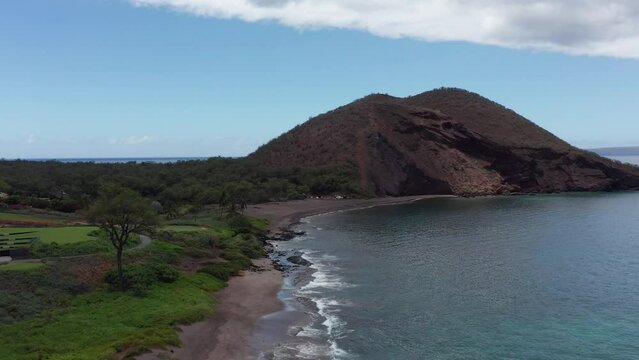 Low rising aerial shot flying over Maluaka Beach towards the cinder cone crater Pu'u Olai in South Maui, Hawai'i. 4K