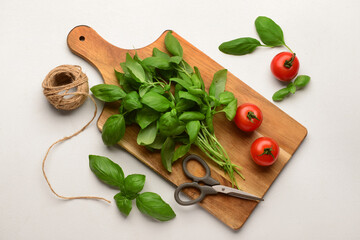 Wooden board with fresh green basil and tomatoes on white background