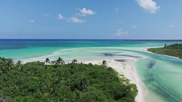 Drone ascends diagonally above estuary and white sandy beach overlooking stunning coastline of Tulum