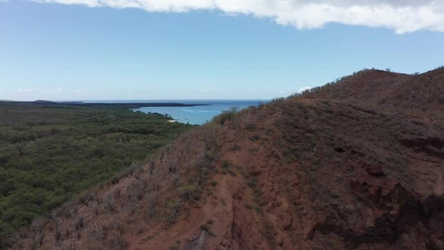 Low aerial shot flying over the Pu'u Olai cinder cone crater to reveal Makena State Park and Beach off the southern coast of Maui in Hawai'i. 4K