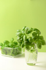 Glass and bowl with fresh green basil on white table