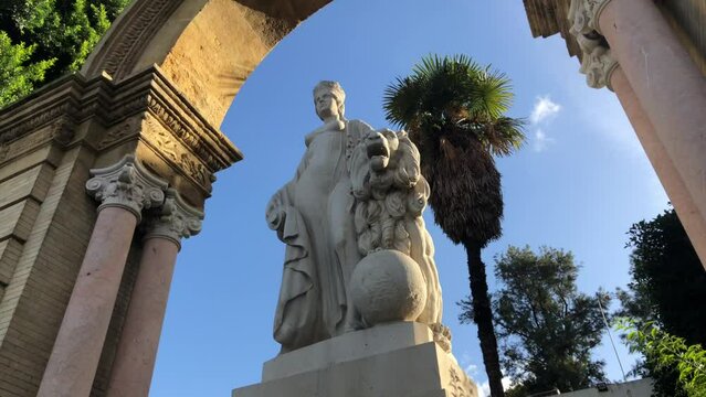 Orbital shot of monumental fountain in Mara Luisa Park, Seville, Spain. Female figure wearing crown accompanied by lion.