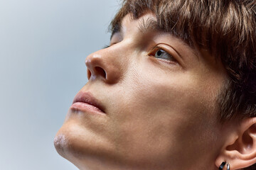 Fresh, male face. Cropped closeup portrait of young attractive brunette man looking away against over grey studio background. - obrazy, fototapety, plakaty