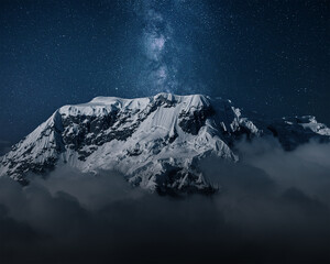 Milky Way above mountains in fog at night in autumn. Landscape with himalayan mountains, low clouds, purple starry sky with milky way  - obrazy, fototapety, plakaty