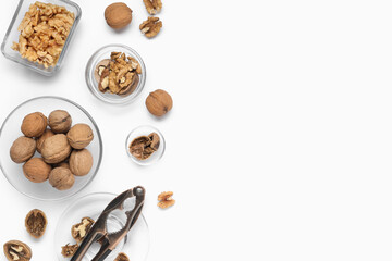 Bowls with walnuts and nutcracker on white background