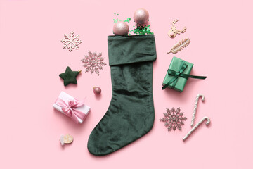 Beautiful Christmas sock with gift boxes and decorations on pink background