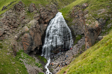 Obraz premium Mountain landscape with waterfall. natural background, trekking, mountain walks, healthy and active lifestyle. Girl's braids waterfall