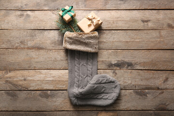 Beautiful Christmas sock with gift boxes and fir branch on wooden background