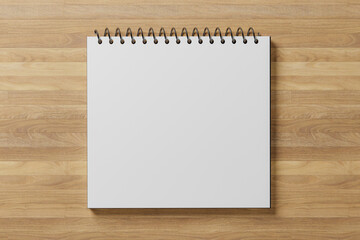 white blank notepad sheet mockup. spiral calendar on wooden table. square shape notebook. top view....