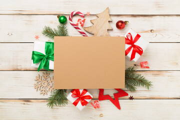 Fototapeta na wymiar Greeting card mockup with christmas decor on wooden background, top view
