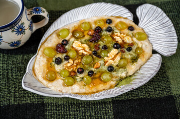 Porridge oatmeal with fruit, nut, honey and moringa powder in fish-shaped plate.