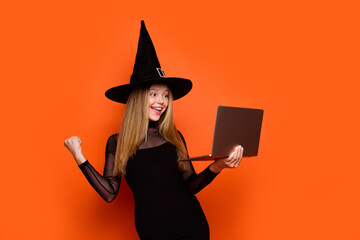 Photo portrait of attractive blonde teen woman laptop raise fist lucky dressed black halloween...