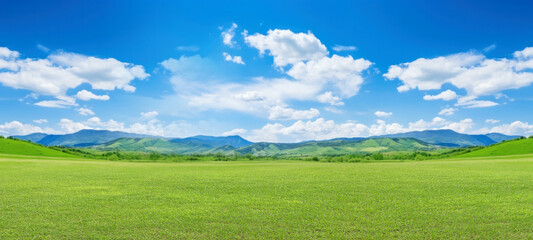 Green grass field on slope with blue sky and clouds background, cloud mountain tropic valley landscape, wide misty panorama