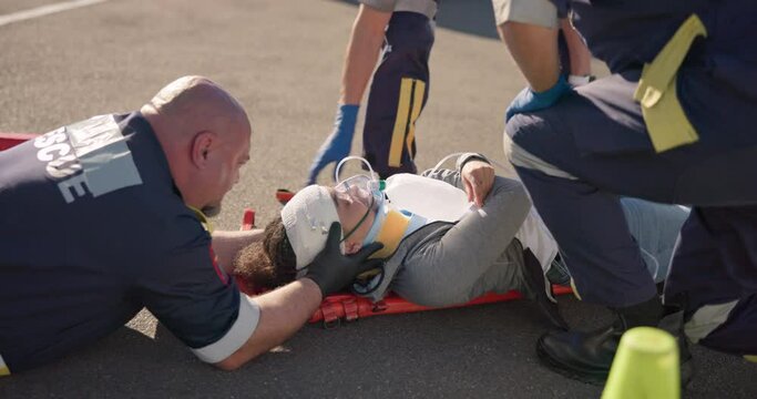 Hands, emergency oxygen and an emt team with a patient or victim on the street for accident treatment. Healthcare, medical or first aid with a paramedic group working to rescue a person from above