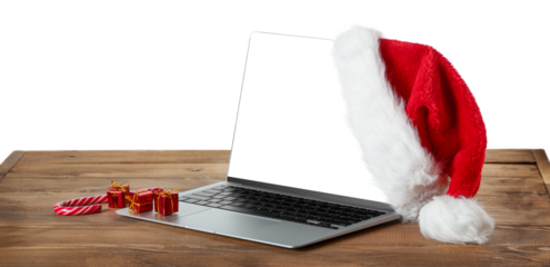 Laptop with blank screen and Santa hat on wooden rustic table. 