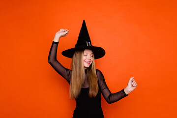 Photo of cute carefree lady wear black wizard costume cap dancing having fun isolated orange color background