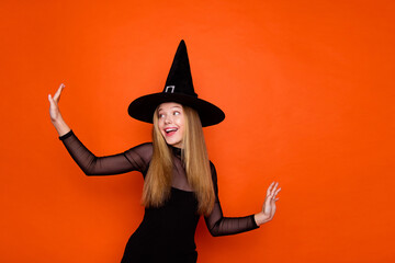 Photo of pretty charming girl dressed dark witch dress headwear having fun dancing isolated orange color background