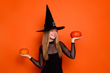 Photo of enchant costume cute girl look arms hold pumpkin empty space isolated on orange color background