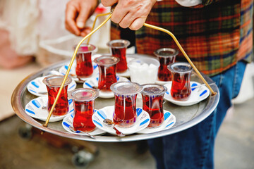 Fototapeta premium Turkish tea in traditional glass mugs on a metal tray. Street vendor selling hot tea in Istanbul, Turkey, Grand Bazaar.
