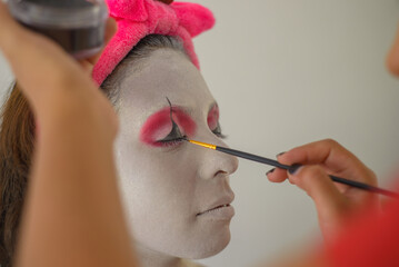 Woman being made up as a clown.