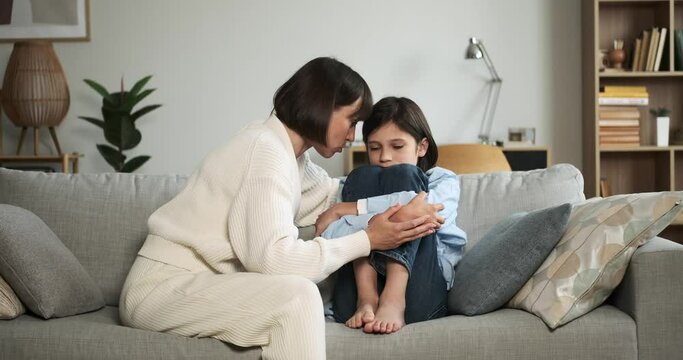 Mother lovingly comforts upset son, giving him a tender kiss to reassure him. Their bond and her soothing gesture bring solace in a moment of distress.