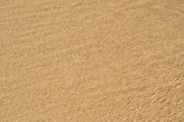 Background with coastal sand. A well-groomed shore with clean yellow sand.