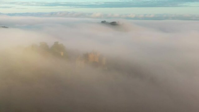 Aerial of Dunster Castle emerging from morning mist in Exmoor, Somerset, England