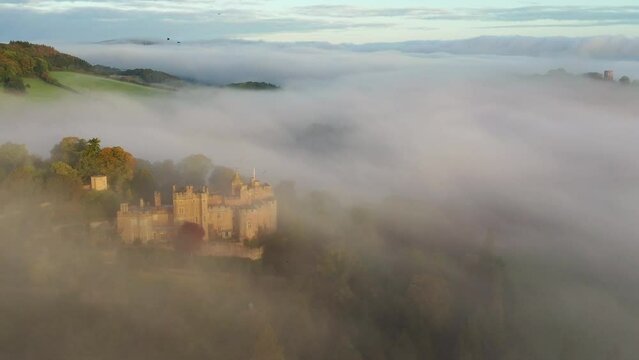 Aerial of Dunster Castle emerging from morning mist in Exmoor, Somerset, England