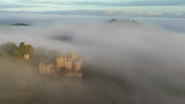Aerial of Dunster Castle emerging from morning mist in Exmoor, Somerset, England