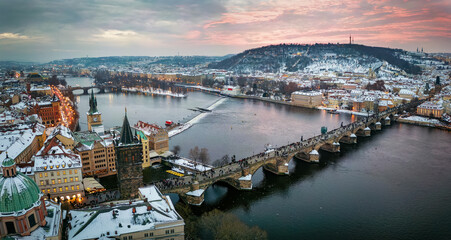 Panoramic view of the snow covered cityscape of Prague, Czech Republic, with Charles Bridge and the old town during winter sunset time