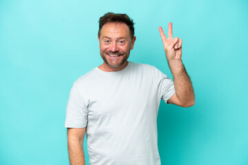 Fototapeta premium Middle age caucasian man isolated on blue background smiling and showing victory sign