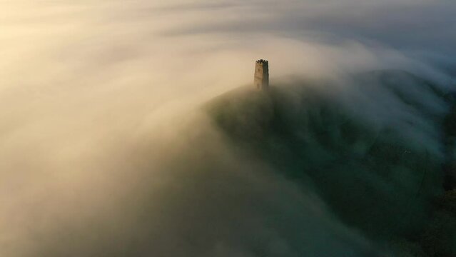 Aerial of Glastonbury Tor on a misty autumn morning above the Somerset Levels, Somerset, England