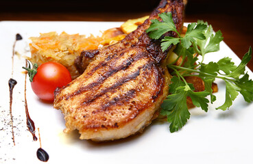 Grilled bone-in steak served with fried potatoes, stewed cabbage and cherry tomatoes on a white square plate