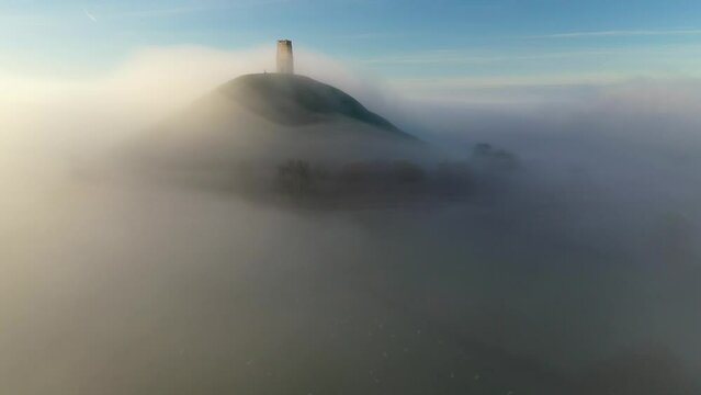 Aerial of Glastonbury Tor on a misty autumn morning above the Somerset Levels, Somerset, England
