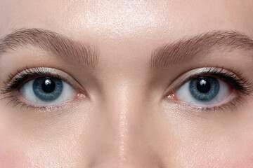 Close-up of beautiful blue eyes of young woman with long lashes