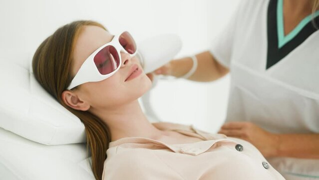 Young woman having laser hair removal procedure in cosmetic center. Removes pigmentation in cosmetic clinic. Intensive Pulsed Light Therapy. Anti-aging treatments.