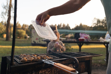 Close-up of a man hand blowing air into the bag coals, cooking grilled mushrooms outdoors on the backyard with family and friends