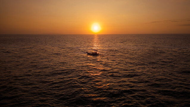 Fisherman boat sailing along The Ocean Against sunset