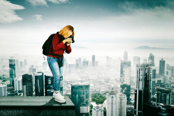 young man with professional camera photographing the city from the top