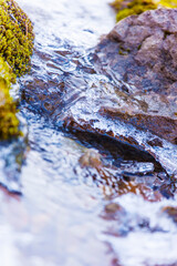 Selective focus. Mountain stream with ice elements close-up