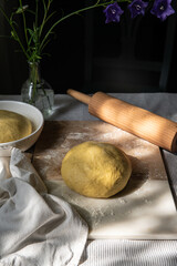 Fresh homemade yeast dough with rolling pin on cutting board .