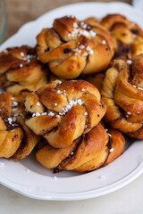 Heap of freshly baked homemade traditional Swedish cinnamon buns ( knots) on beautiful oval white plate. 