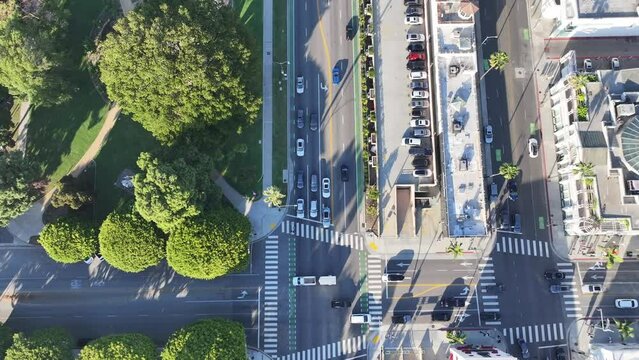 Beverly Hills, Santa Monica Blvd - panning from aerial top view to aerial forward view along Santa Monica Blvd eastbound with traffic on streets and Beverly Gardens Park - aerial video footage 