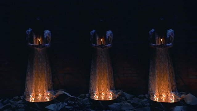 Three creepy figures dressed in bridal gowns standing with candles in a basement. Creepy brides doing witchcraft over pentagram